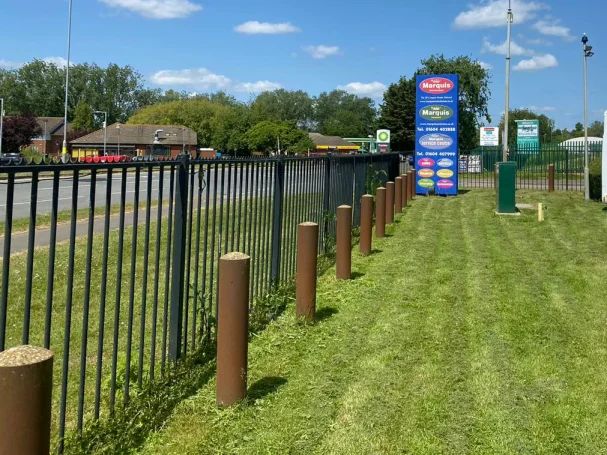 A well-maintained grassy area with a black fence and brown wooden posts.