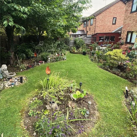 A well-maintained garden featuring a lawn, borders of plants, and decorative ornaments.