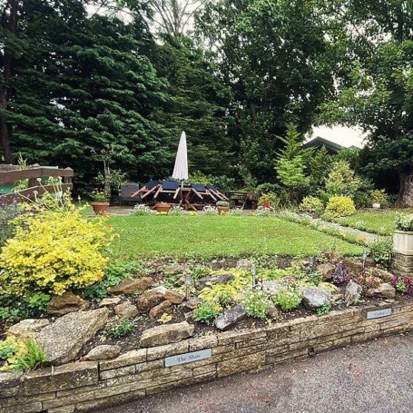 A landscaped garden featuring flower beds, greenery, and a central decorative element.