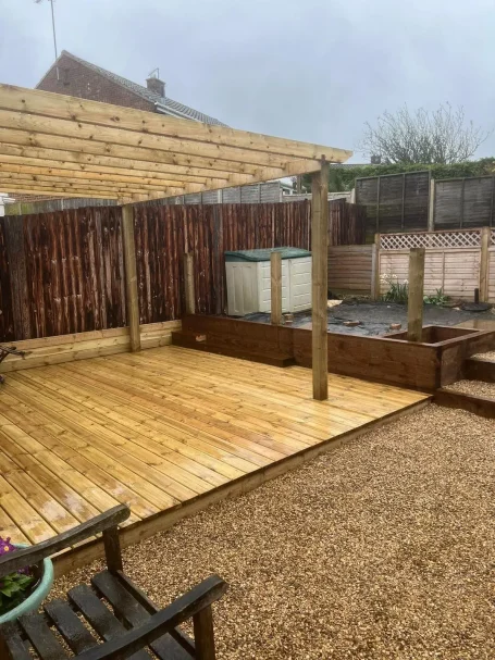 Wooden decking area with a covered pergola and surrounding garden features.