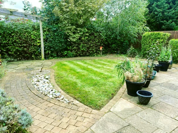 Lawn with neatly trimmed grass, bordered by plant pots and gravel path.