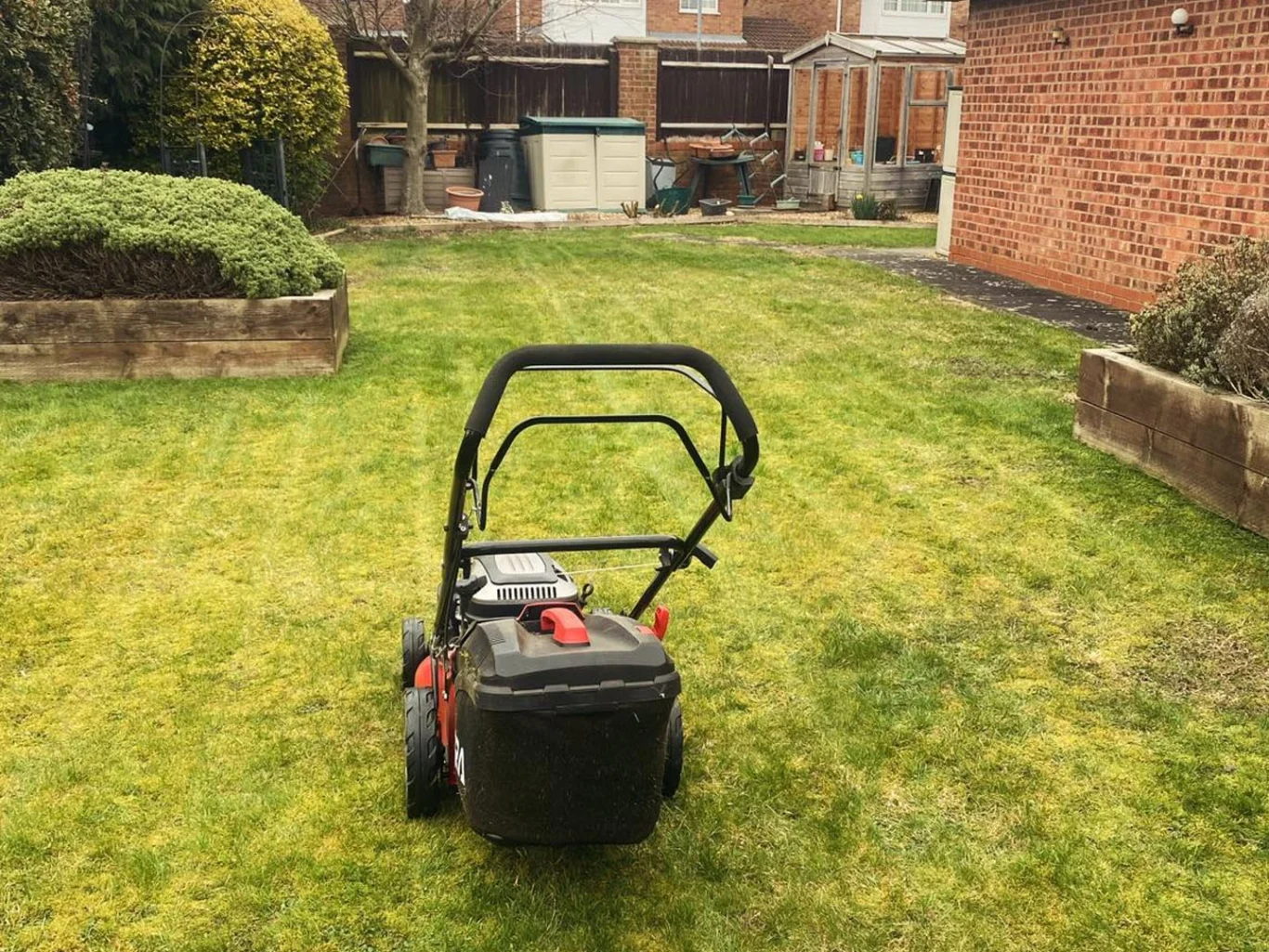Lawn mower on freshly cut grass in a residential garden.