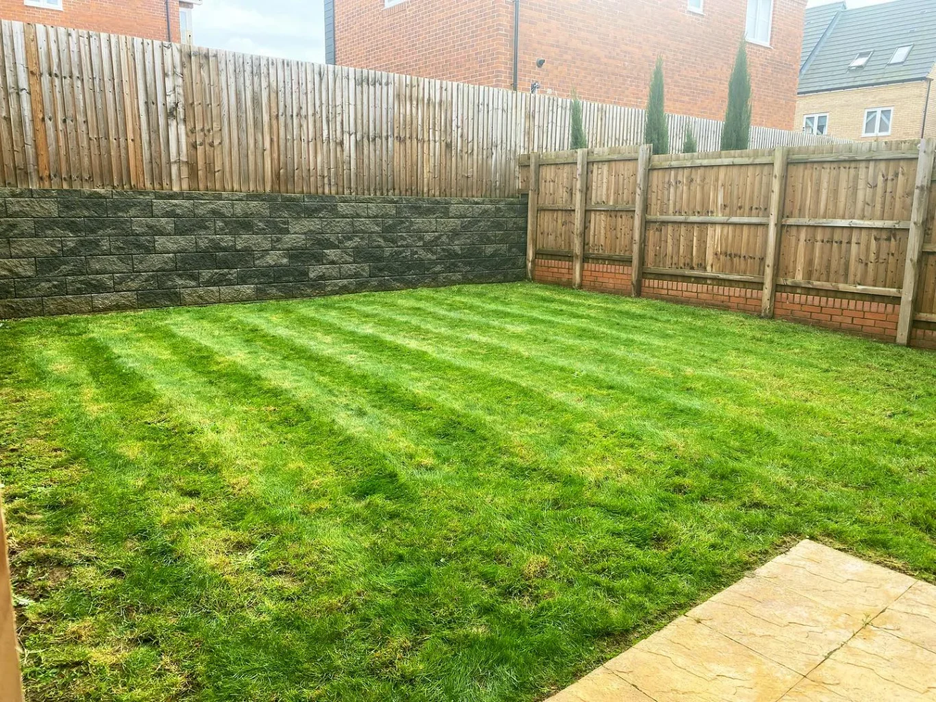 Well-maintained garden with freshly mowed grass and wooden fencing.